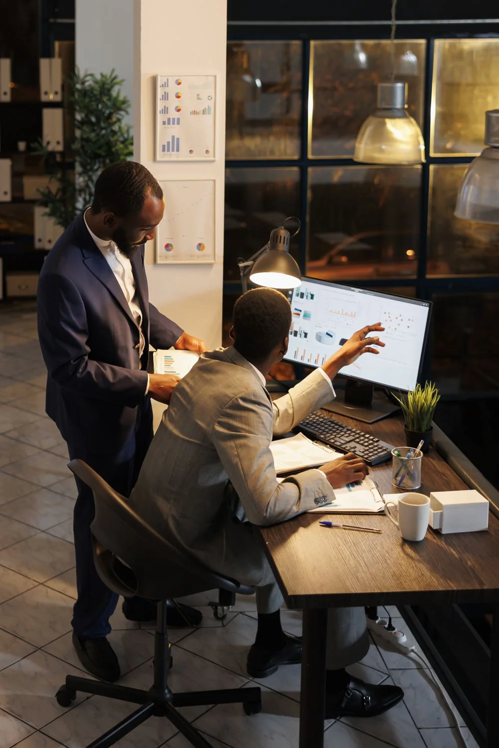 Firstsource: Global BPM Leader 1 Two colleagues reviewing competitor charts on a monitor in a late evening office